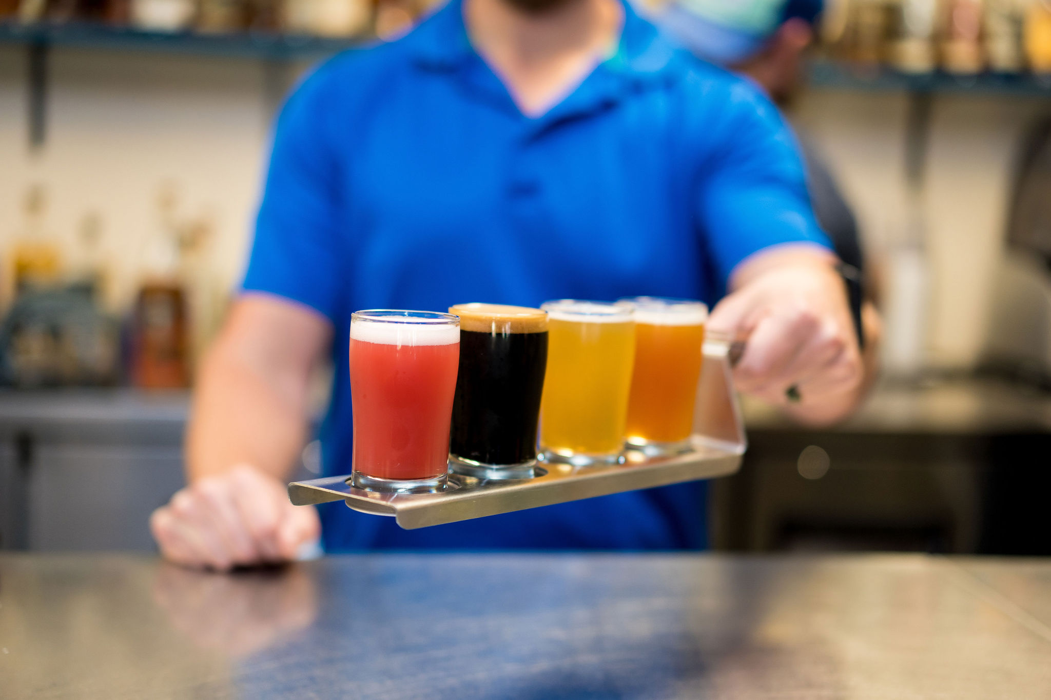 man holding a flight paddle filled for a craft beer tasting experience at Brothers Beer and Bourbon in Creve Coeur