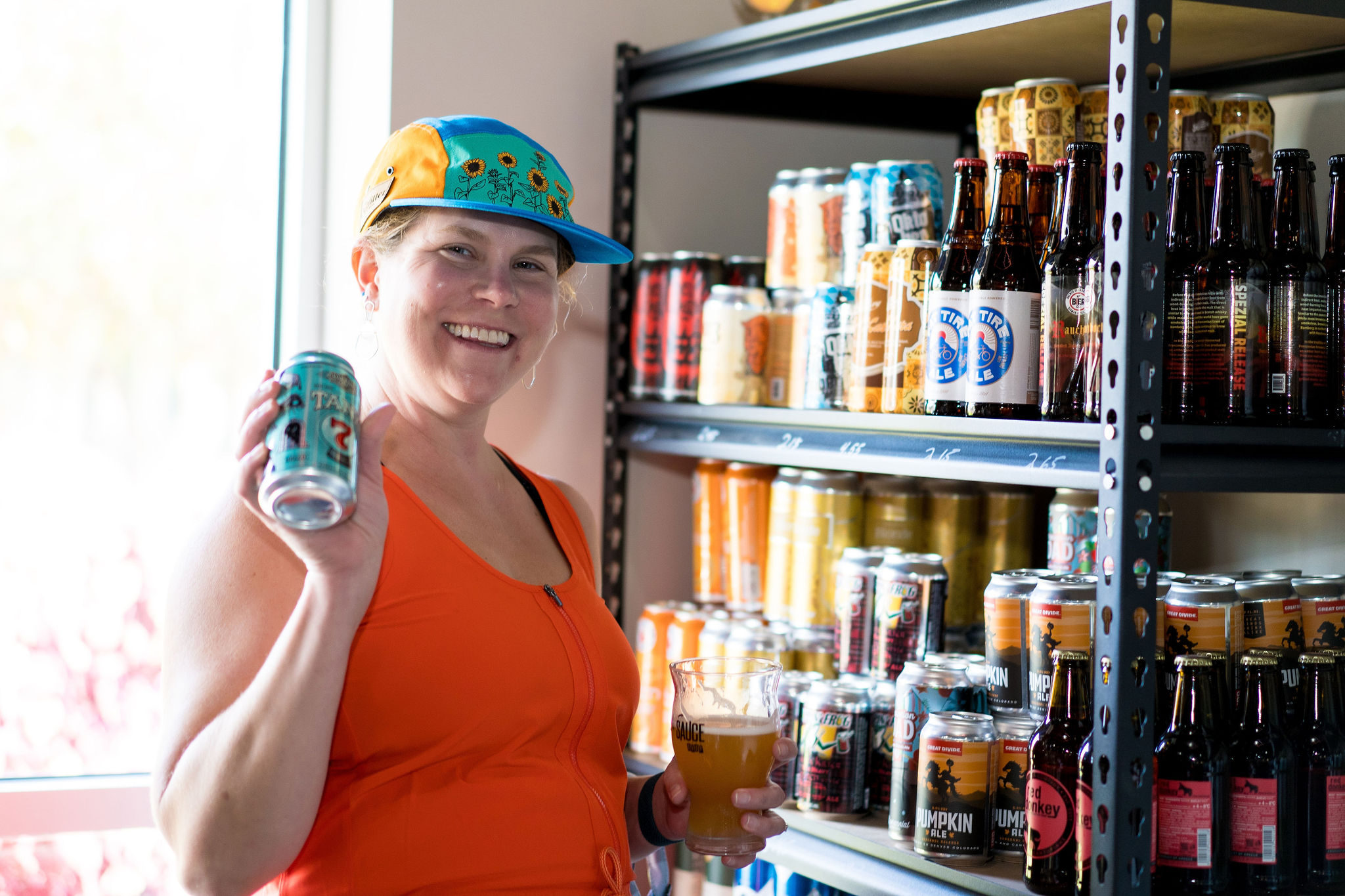 smiling woman holding canned cocktails while shopping at The Brothers Beer & Bourbon House in Creve Coeur